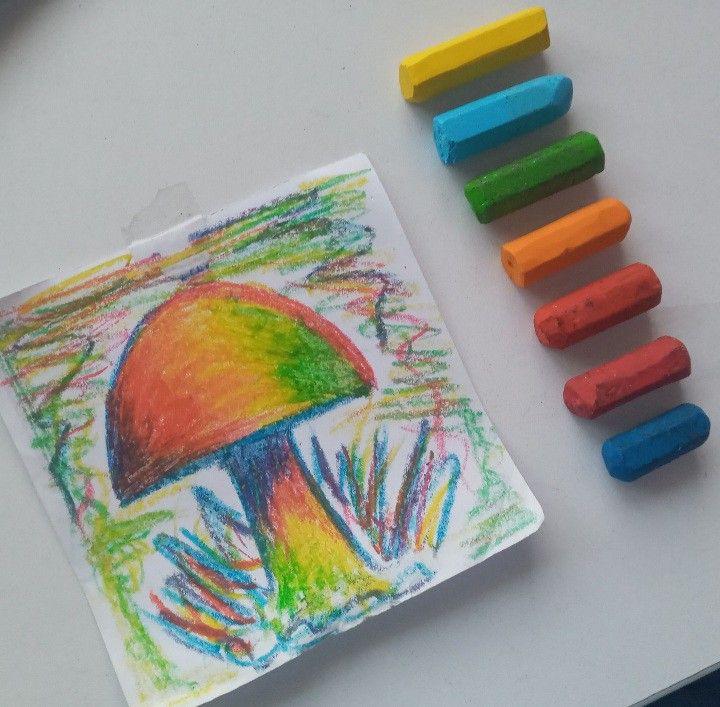 colored crayons are next to a drawing of a mushroom