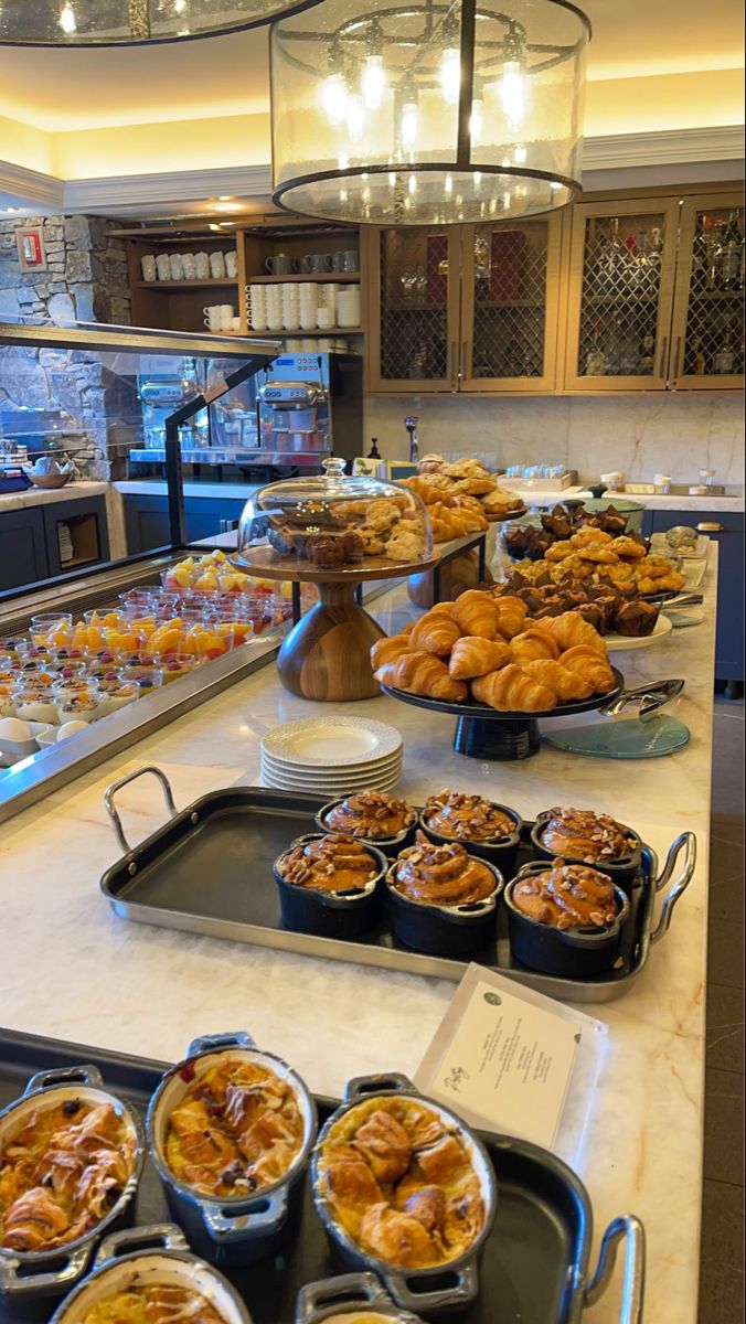 many trays of food sitting on a counter in a restaurant or bakery with an assortment of pastries