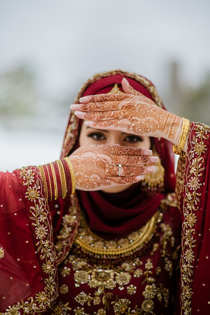 a woman in red and gold holding her hands up to her face with both hands