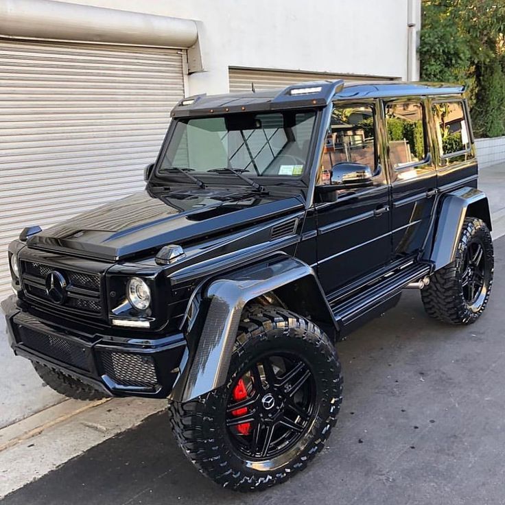 a black mercedes g - class parked in front of a garage