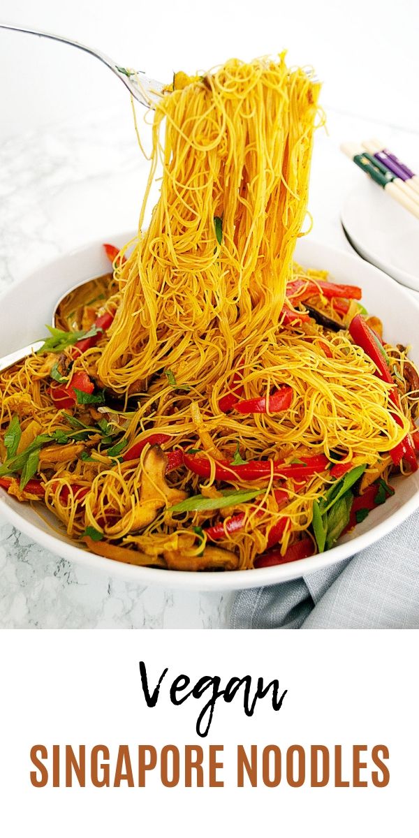 a white plate topped with noodles and veggies on top of a marble table