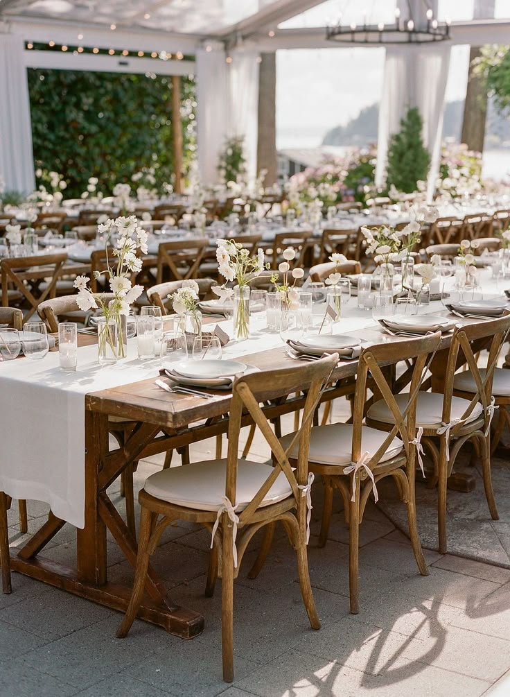 the tables are set with white linens and place settings for guests to sit at