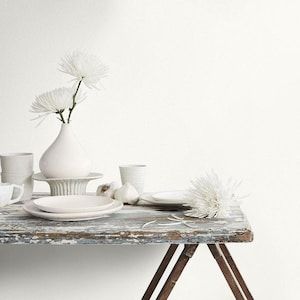 a table topped with white dishes and vases