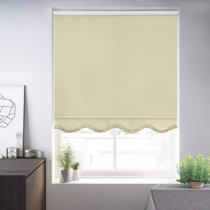 a living room with white walls and a window covered in roman blind shades, along with potted plants