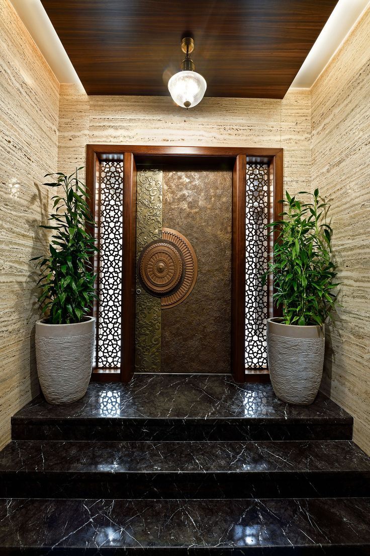 two planters are sitting on the steps in front of an entryway with a decorative door