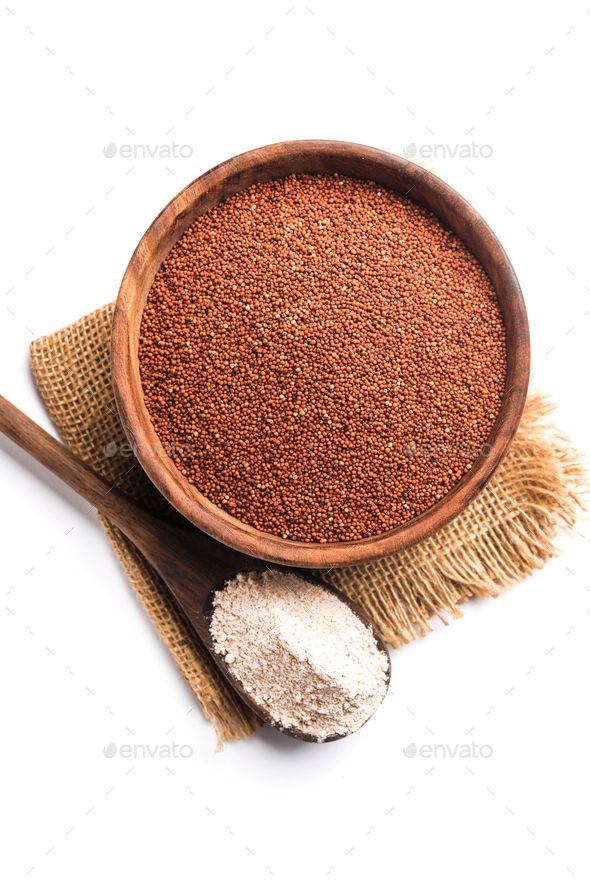 a wooden bowl filled with red and white powder next to a spoon