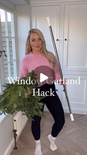 a woman is holding a broom in her hand and standing next to a potted plant