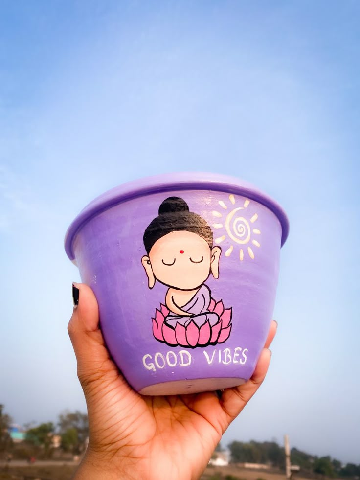 a hand holding up a purple cup with a buddha sticker on it's side