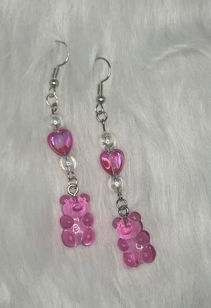 two pink teddy bears dangling from earrings on a white furnishce background with silver beads