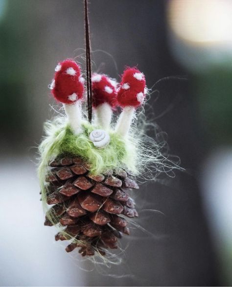 a close up of a pine cone ornament with red mushrooms on it's top