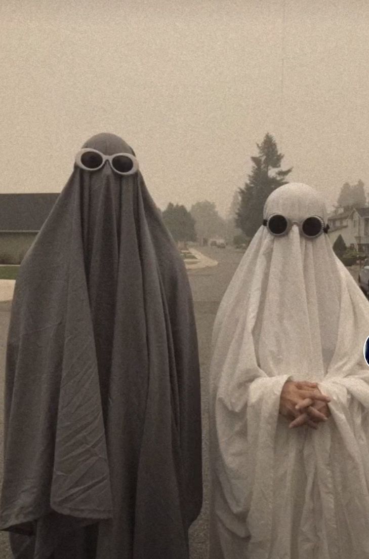 two people dressed as ghostes walking down the street