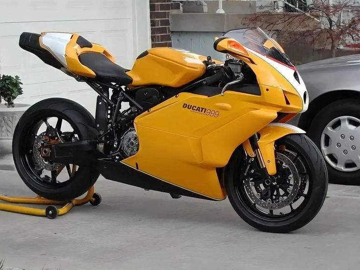 a yellow motorcycle parked next to a silver car