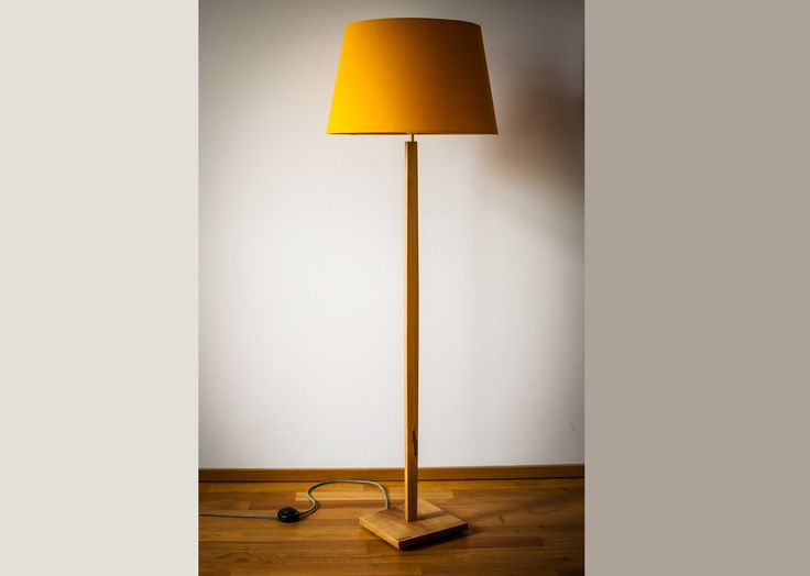 a lamp that is on top of a wooden floor in front of a white wall