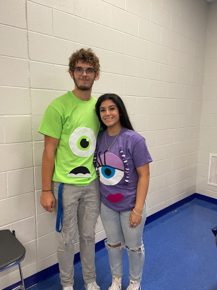 a man and woman standing next to each other in front of a wall with an evil face on it