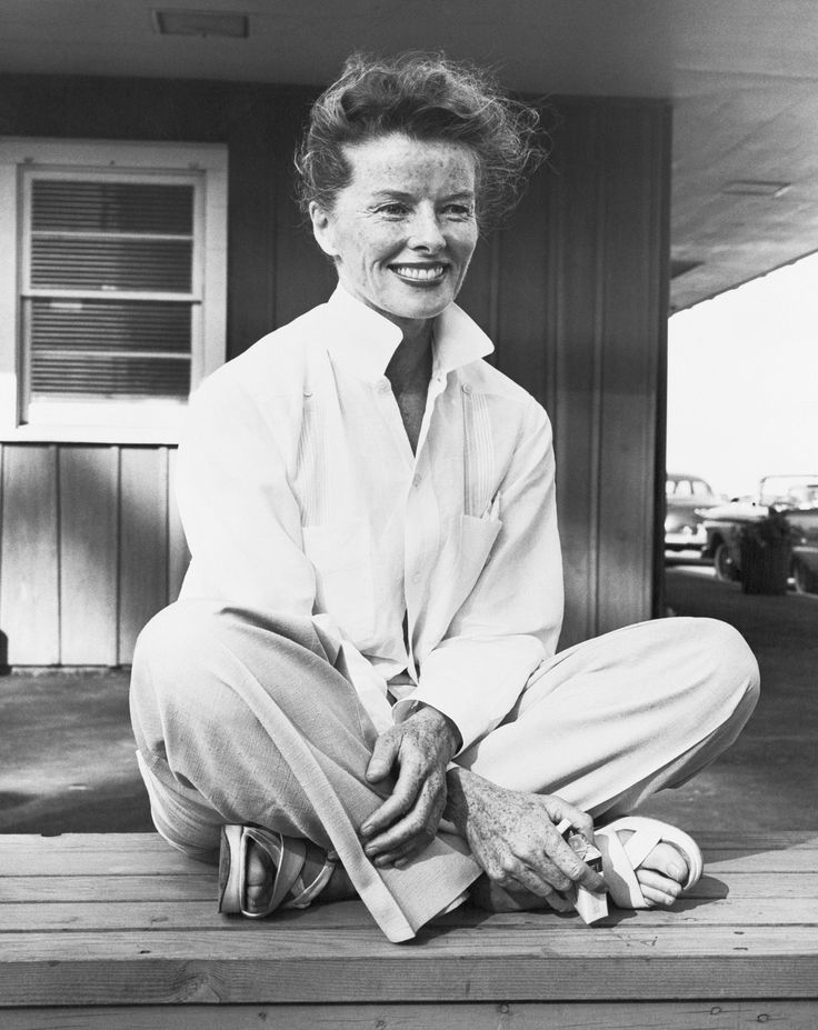 black and white photograph of a man sitting on the porch with his feet crossed in front of him