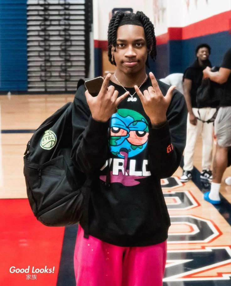 a young man with dreadlocks making the vulcan sign while standing on a basketball court