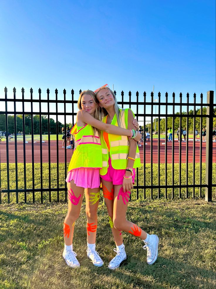 two girls hugging each other in front of a fence