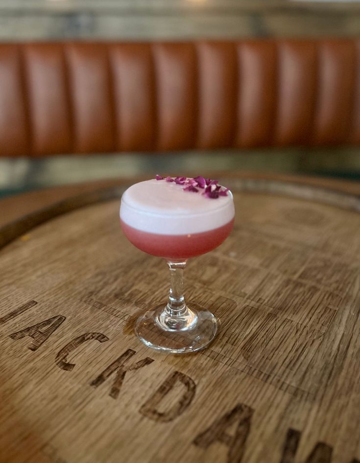 a pink drink sitting on top of a wooden barrel