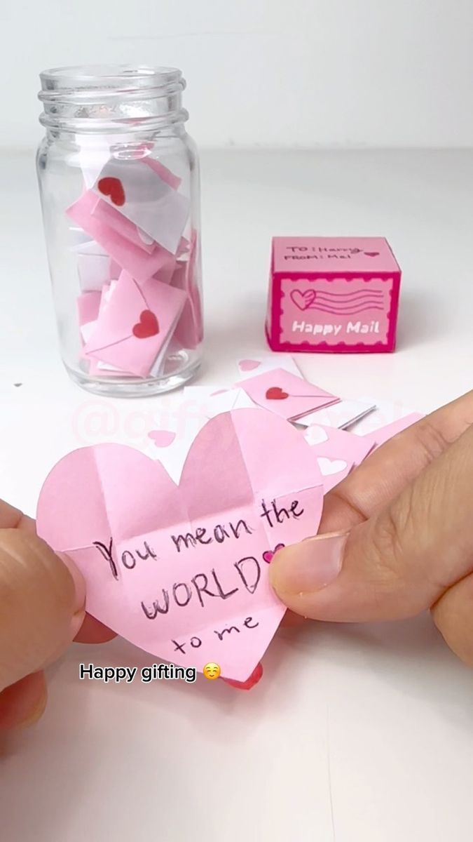 someone is holding up a pink heart shaped card that says you mean the world to me