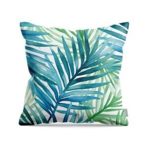 a blue and green palm leaf pillow on a white background