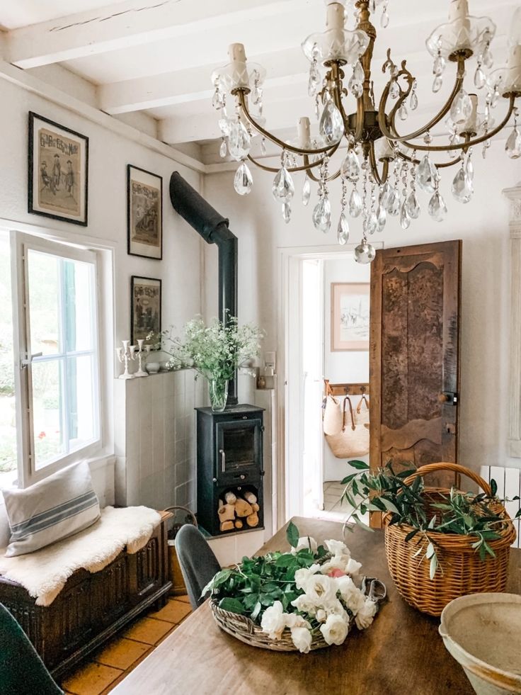 a dining room with a chandelier and potted plants on the table in front of it