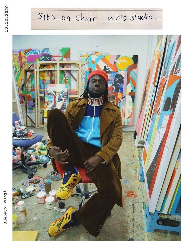 a man sitting on top of a red chair in front of a painting easel