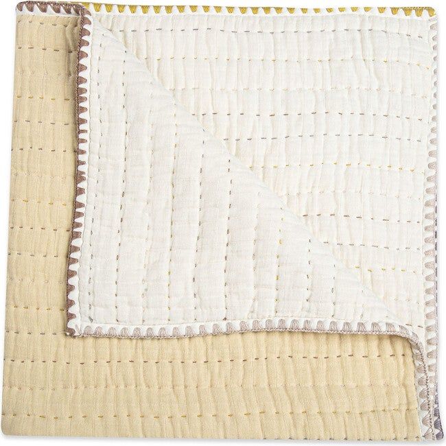 a close up of a blanket on top of a white table cloth with yellow trim