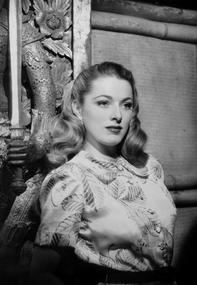 an old black and white photo of a woman in a dress with her arms crossed