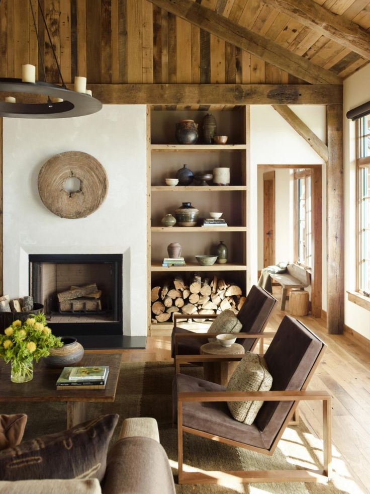 a living room filled with furniture and a fire place in front of a wooden wall