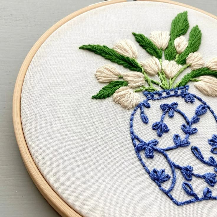 a blue and white vase with flowers in it on a wooden hoop hanging from a wall