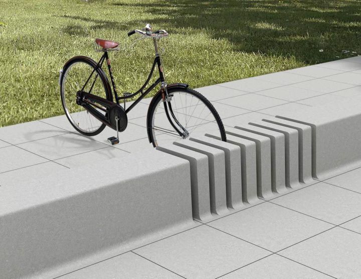 a bike parked on the side of a sidewalk next to a grass covered park area