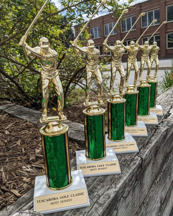 four green glass trophies sitting on top of a wooden table