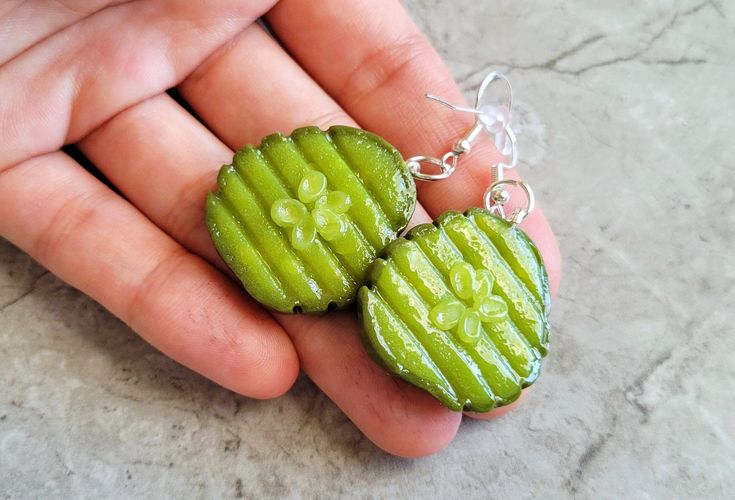 a person holding some kind of green item in their hand with it's earring