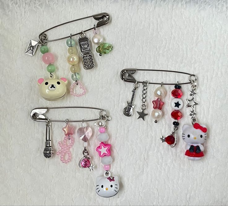 two hair clips with charms attached to them on a white surface, one has a hello kitty charm