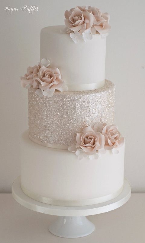 a three tiered white cake with pink flowers on top