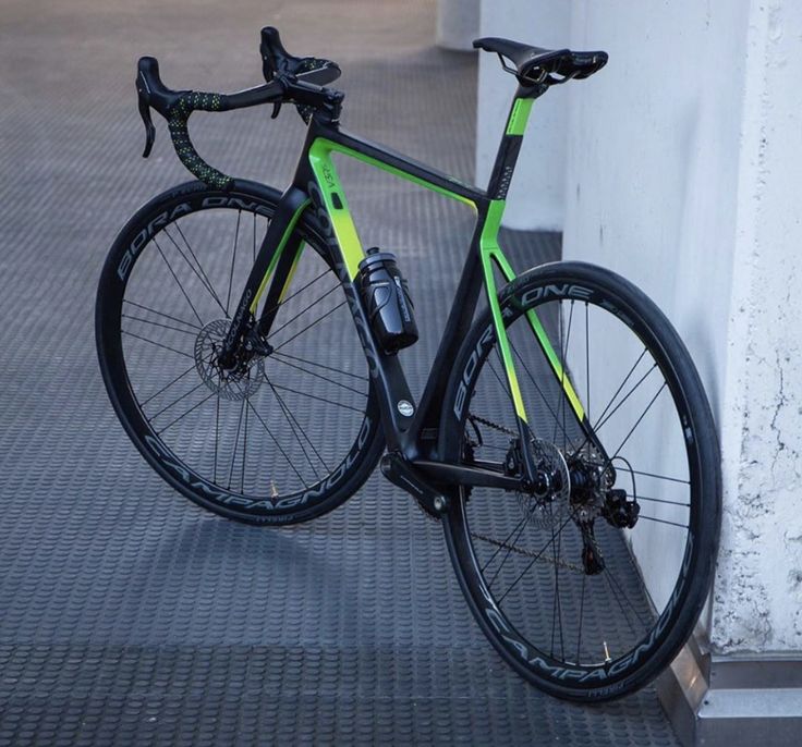 a green and black bike leaning against a wall