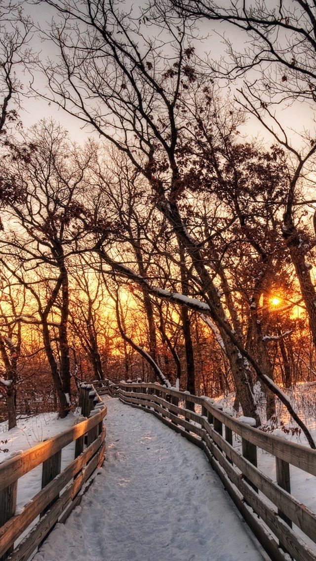 the sun is setting over a snowy path