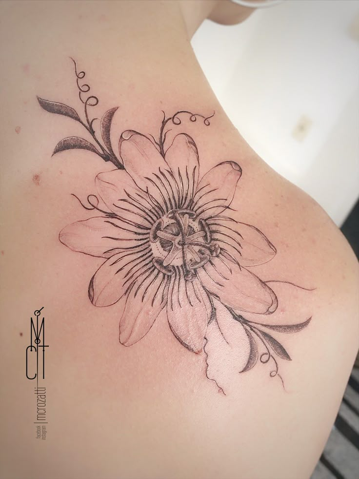 a woman's back with a flower tattoo on it