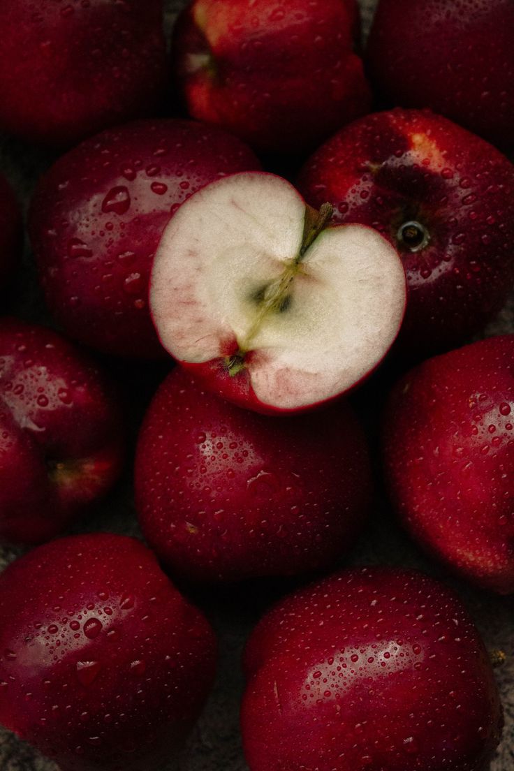 a pile of red apples sitting next to each other on top of a table covered in water droplets