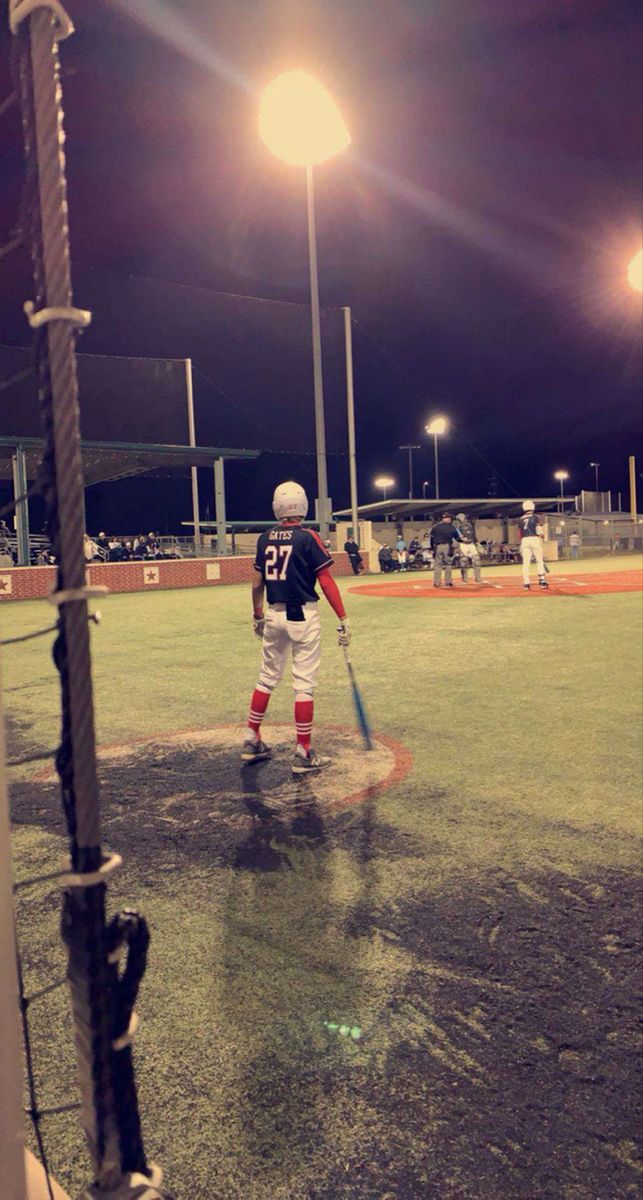 a baseball player holding a bat on top of a field in the rain at night