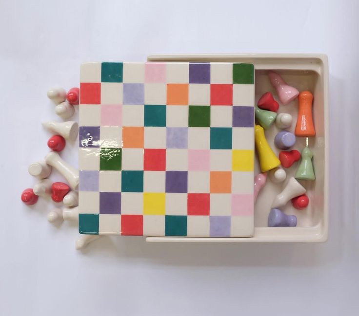 a colorful checkerboard board with candy in it on a white tablecloth background