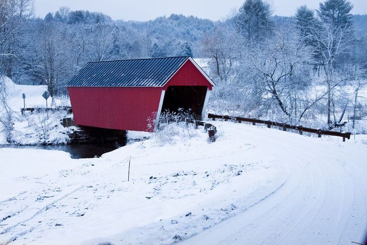 a red covered bridge in the middle of winter