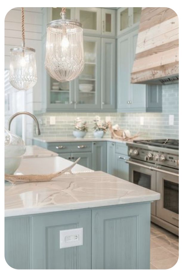 a kitchen with blue cabinets and marble counter tops, two chandeliers hanging from the ceiling