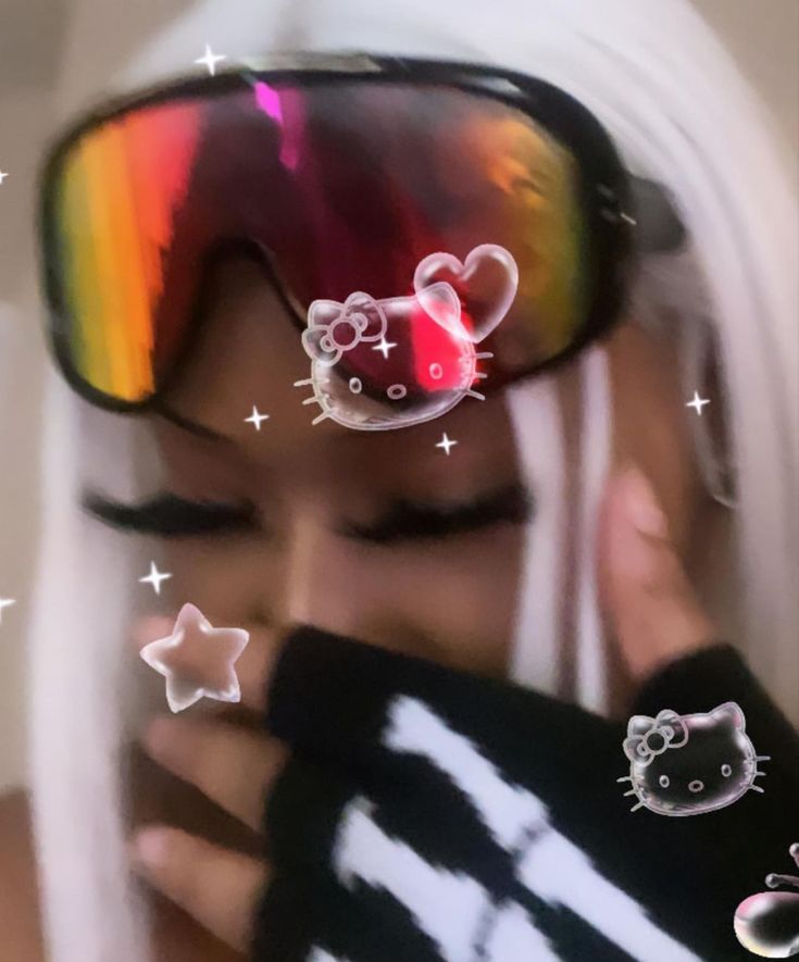 a woman wearing hello kitty goggles and holding her face to the side with stars around her