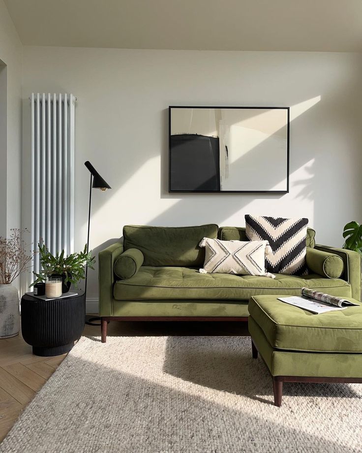 a living room with a green couch and ottoman in front of a white curtained window