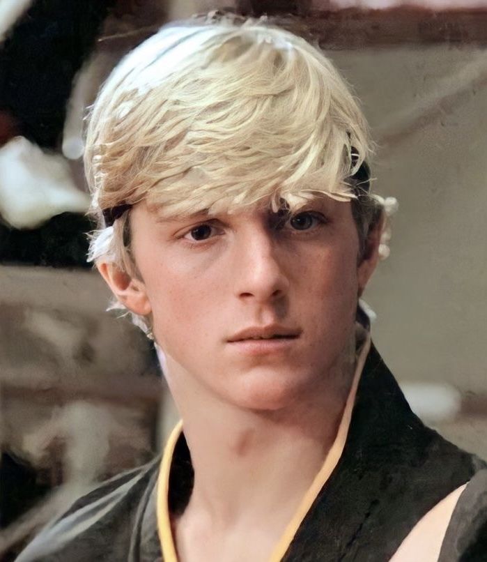 a young man with blonde hair wearing a black shirt