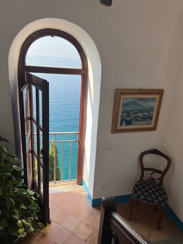 an open door leading to a balcony with a view of the ocean in the distance