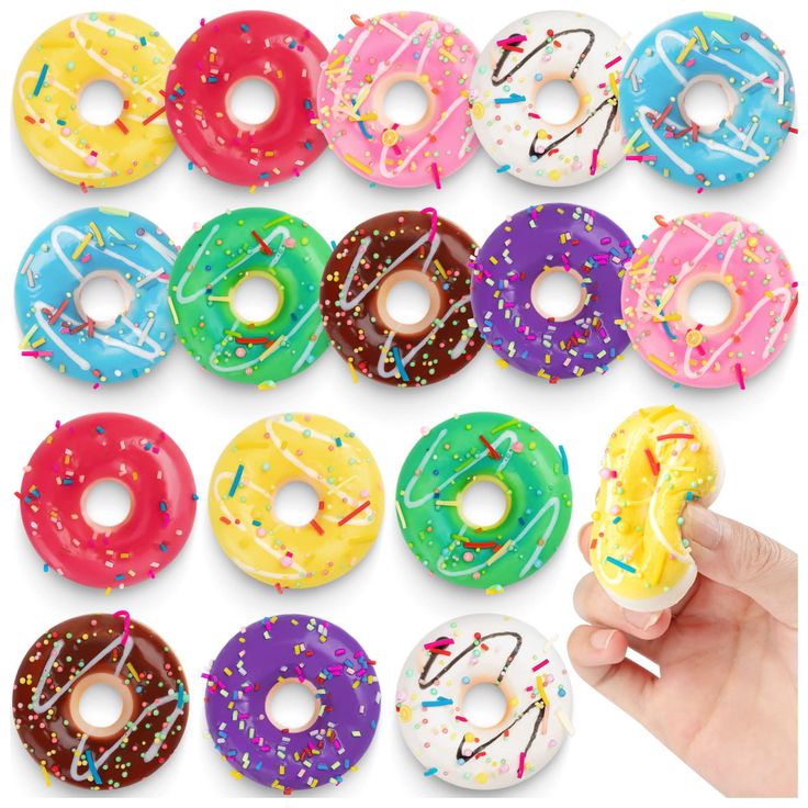 a hand holding a doughnut with sprinkles on it in front of a group of donuts