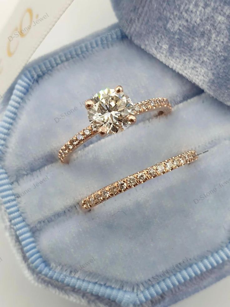 two diamond engagement rings in a blue velvet box