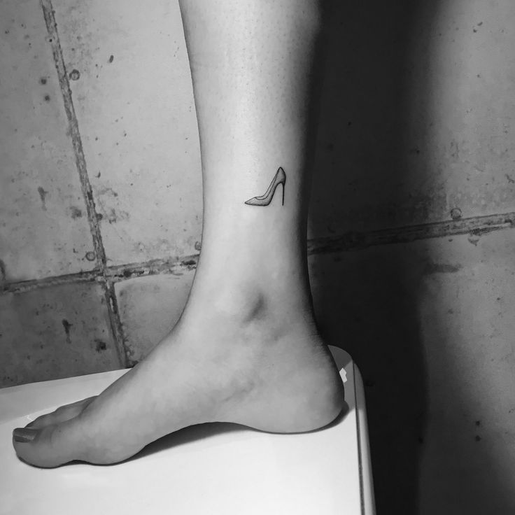 a black and white photo of a woman's foot with a high heel tattoo